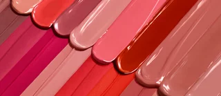 Farbenfrohe Anordnung von Nagellack in verschiedenen Rosa- und Nude-Tonen.