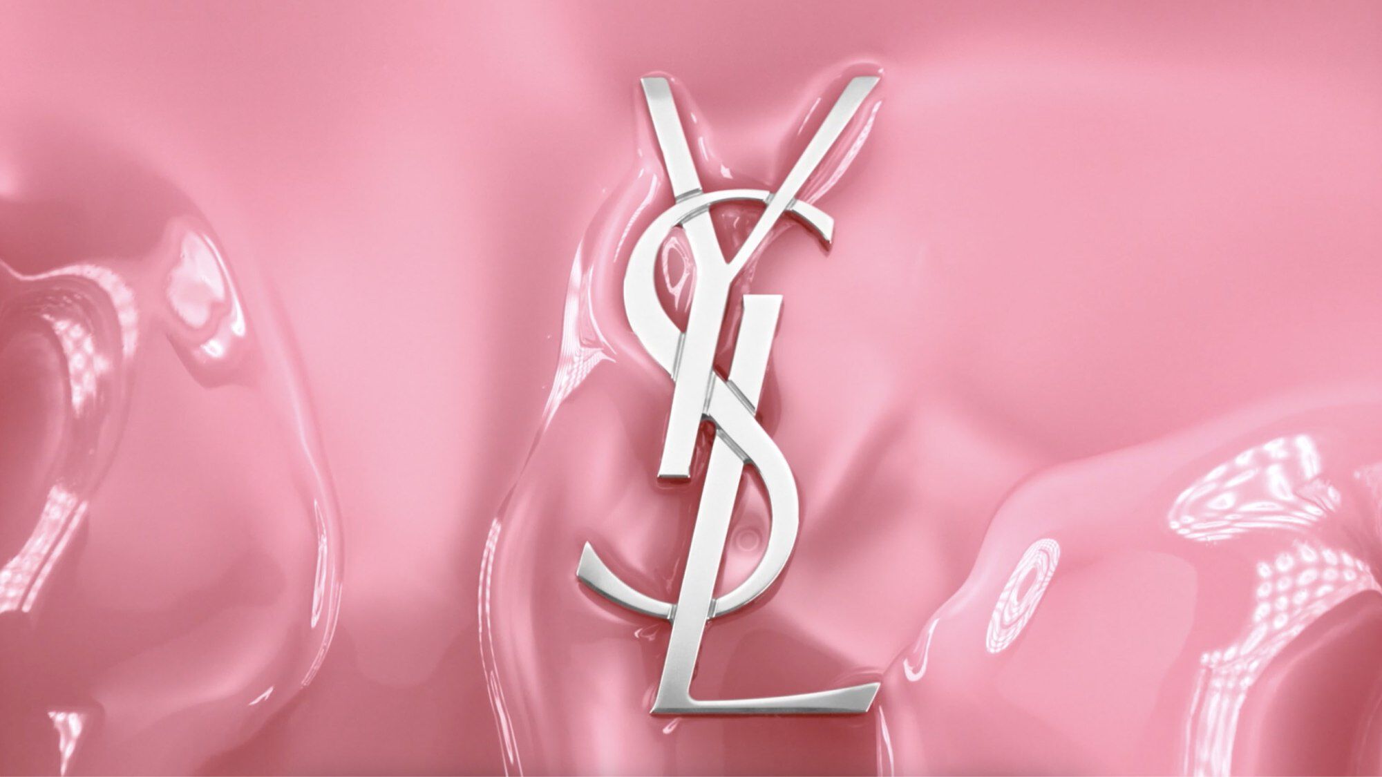 A stylized silver "YSL" logo on a smooth pink background.