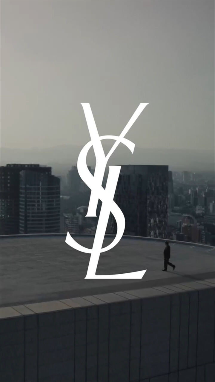 YSL-Logo uber einer Dachterrasse mit Skyline bei Sonnenuntergang