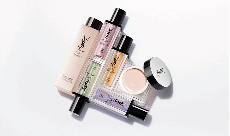 A flat lay of various YSL beauty products, including foundations, serums, and creams, arranged artistically on a clean, light background.