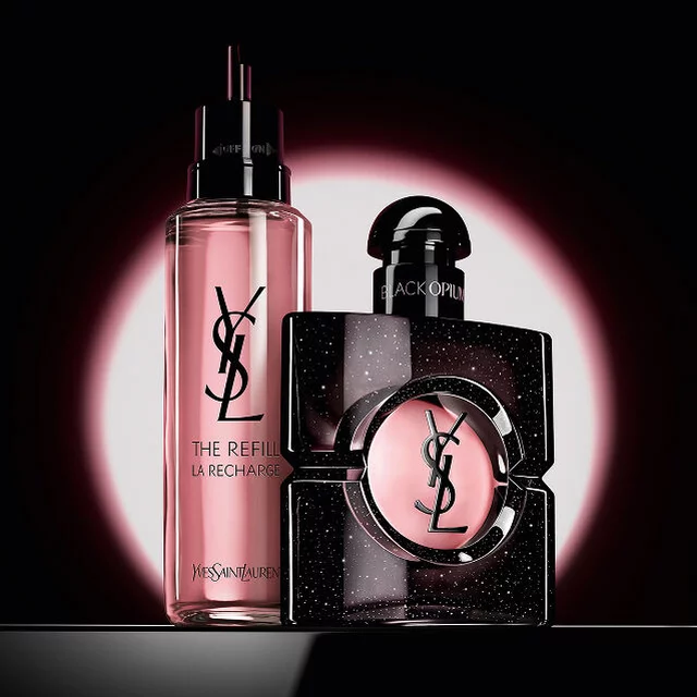 Black Opium Eau de Parfum Flakon neben seiner 100-ml-Glas-Nachfullflasche mit dem YSL-Logo.