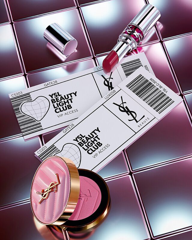 Make Me Blush, Loveshine lipstick, and two YSL Beauty Light Club VIP tickets on a reflective tiled background.