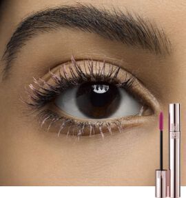 Close-up of a woman's eye showcasing long, defined eyelashes, with a pink lip gloss tube positioned beside it.