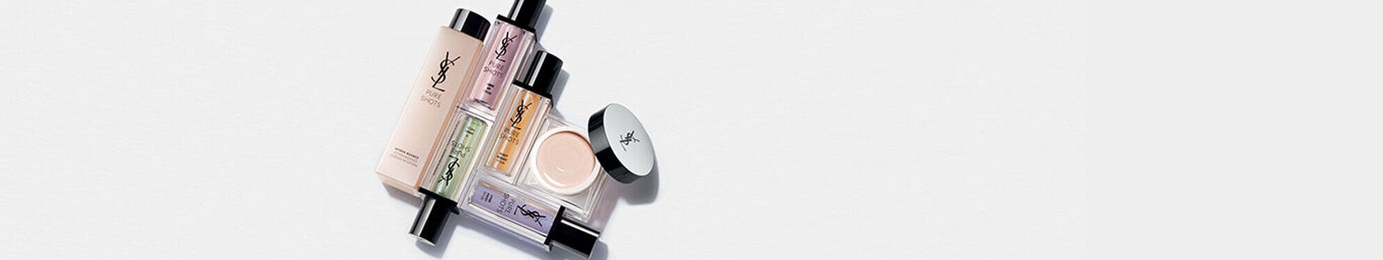 A collection of various makeup products arranged neatly, including foundations, concealers, and primers, against a white background.