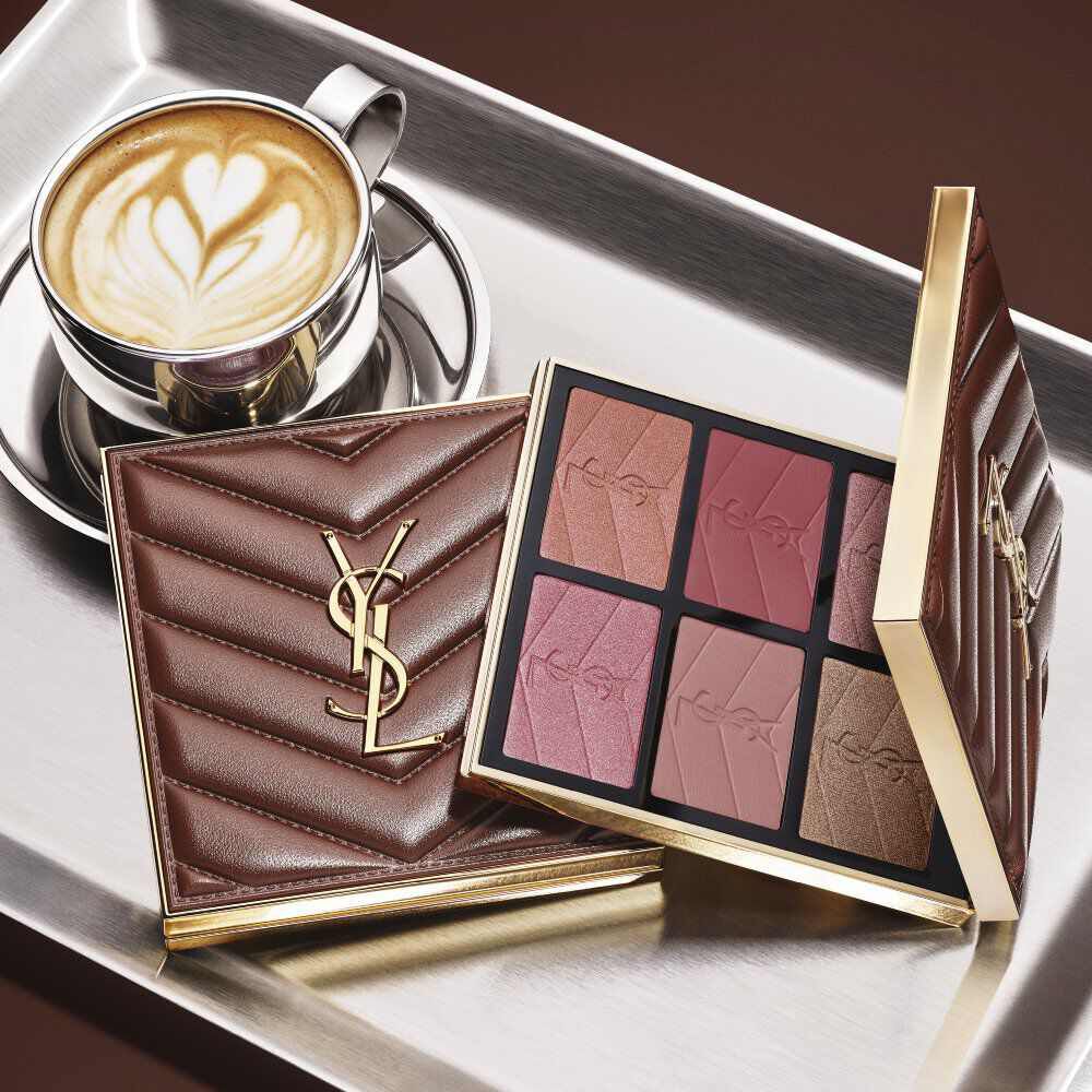 YSL-Make-up-Palette und gesteppte Clutch neben einem Kaffee auf einem silbernen Tablett.