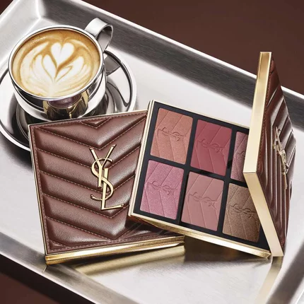 YSL-Make-up-Palette und gesteppte Clutch neben einem Kaffee auf einem silbernen Tablett.