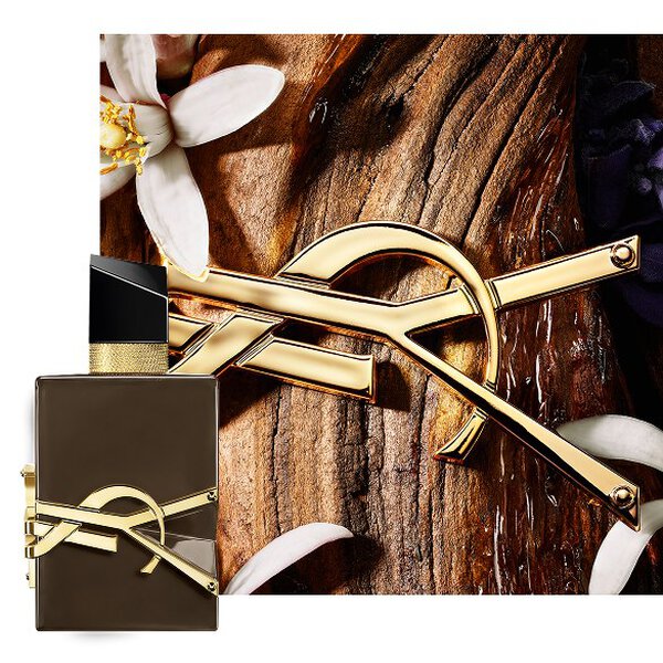 Libre Santal Couture braune, glasierte Flakon auf Sandelholzrinde mit goldener Cassandre und weißen Bluten.