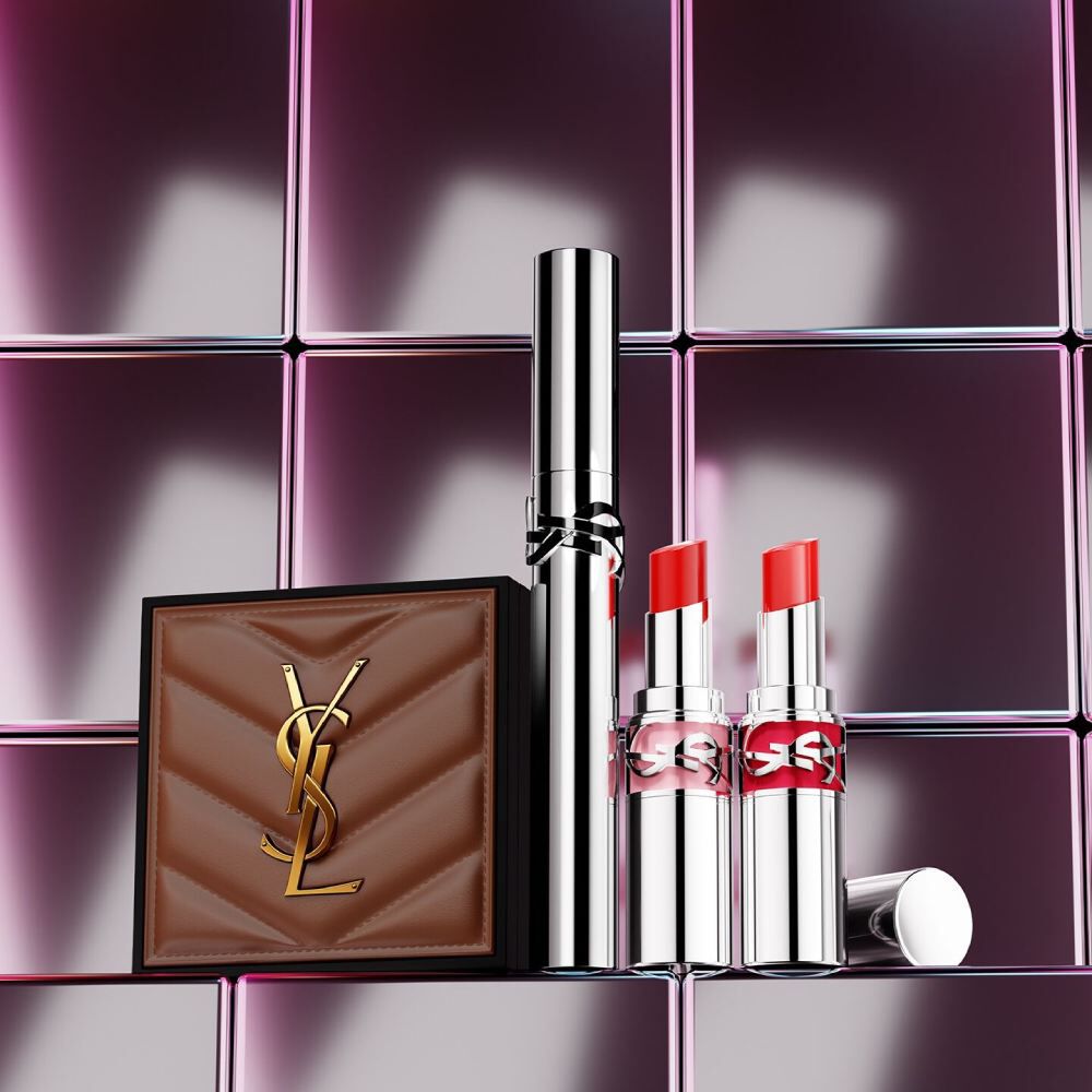YSL Beauty-Produkte, darunter eine gesteppte Dose, Mascara und zwei Lippenstifte vor glanzendem, rosa gefliestem Hintergrund.