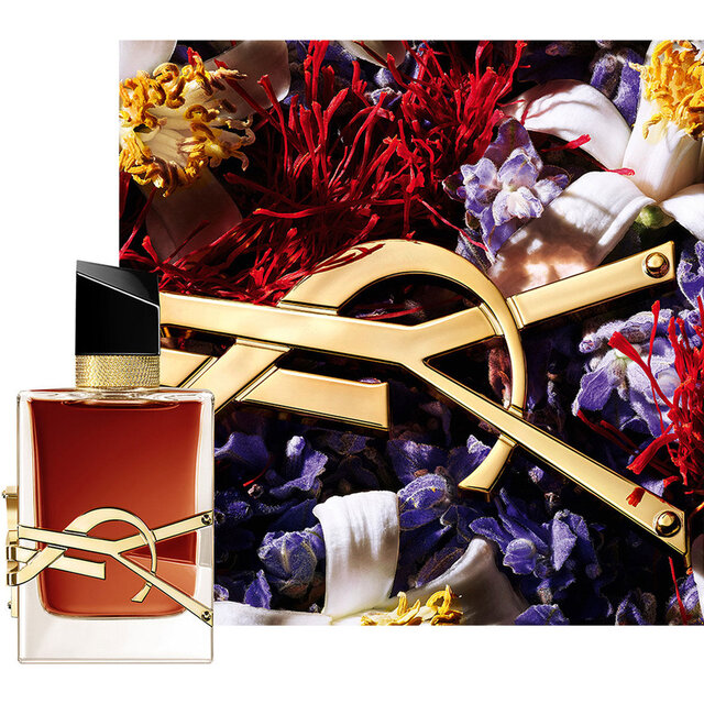 LIBRE LE PARFUM Flakon, inszeniert mit roten floralen Elementen und goldenem YSL Logo.