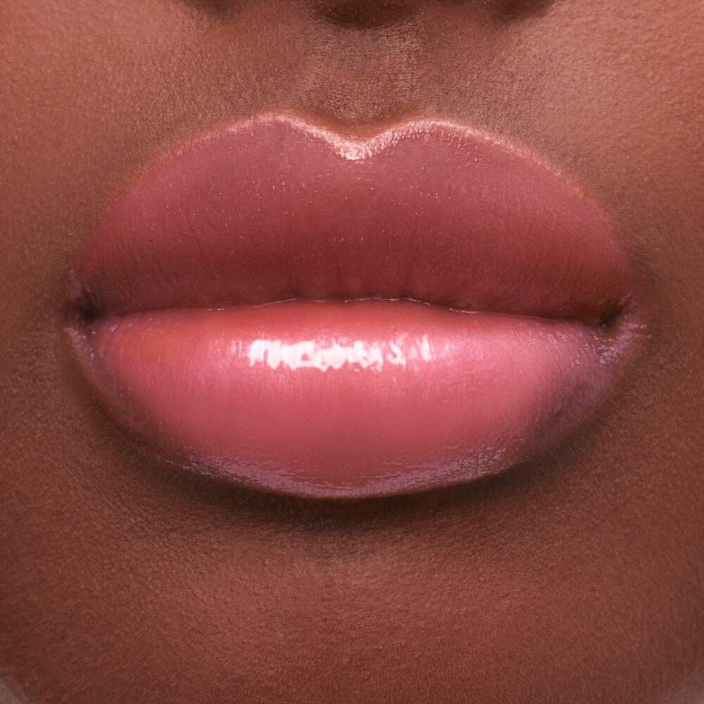 Close-up of smooth, full lips covered in a glossy, light pink lip color against a dark skin tone.