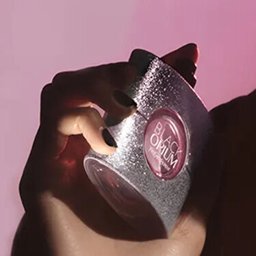 Rote YSL-Geschenkbox mit rosa Blumen auf rotem Hintergrund.