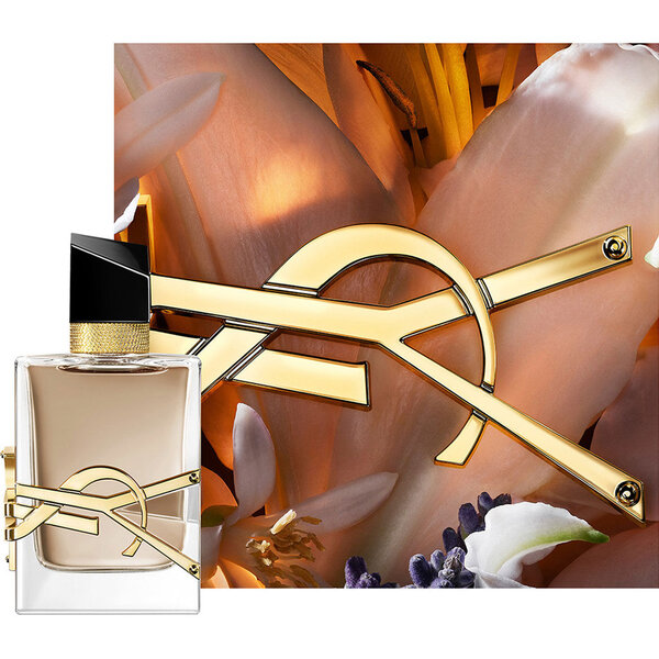 LIBRE FLOWERS & FLAMES Flakon, gerahmt von cremigen Blutenblattern und goldenem YSL-Logo im warmen Licht.