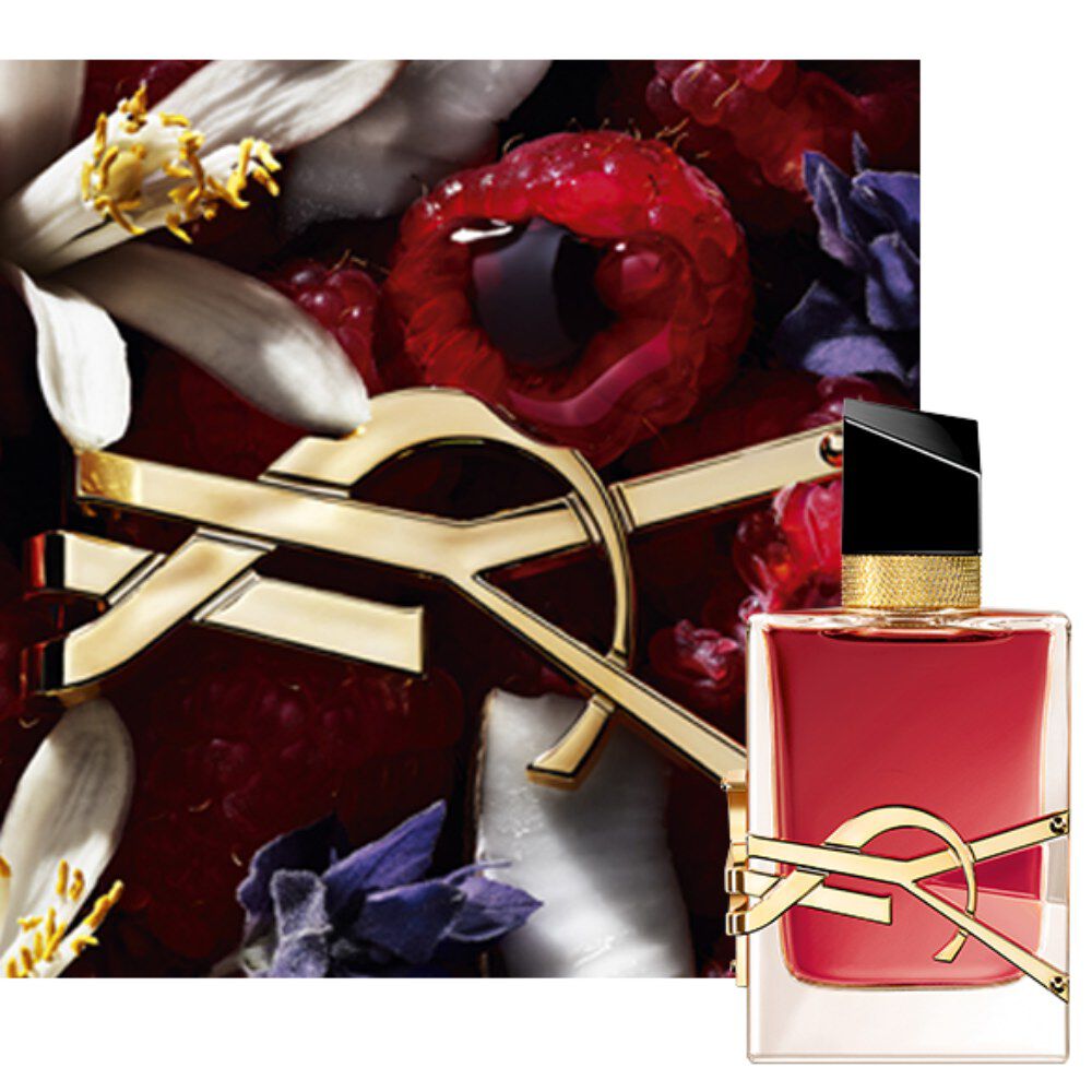 Nahaufnahme des Flakons Libre Berry Crush mit goldenem YSL-Logo, umgeben von roten Beeren und floralen Elementen.