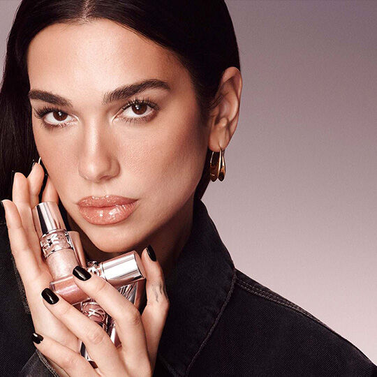 Dua Lipa posiert mit YSL Loveshine Lippenstiften..​