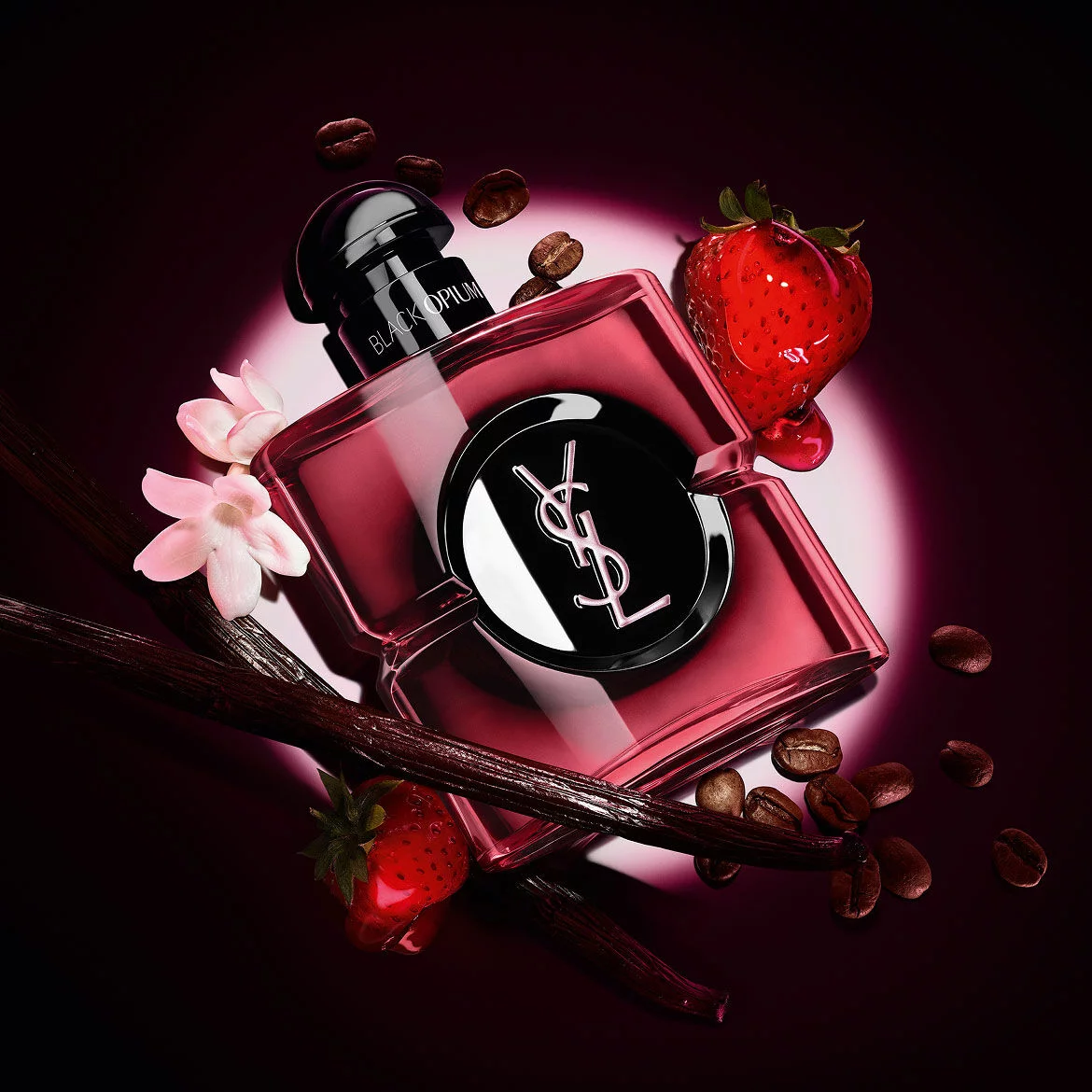 Black Opium Eau de Parfum Pink Glaze Flakon, umgeben von frischen Erdbeeren, Vanilleschoten, Kaffeebohnen und Jasmin.