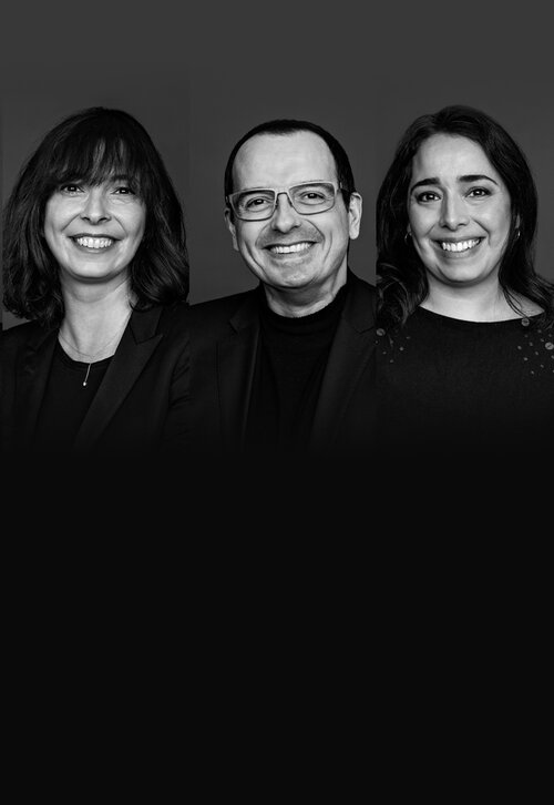 A monochrome portrait featuring four individuals standing side by side, each displaying warm smiles.