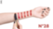 A hand with polished nails applies lipstick on a forearm displaying swatches of various shades of red lipstick labeled with the number 28.