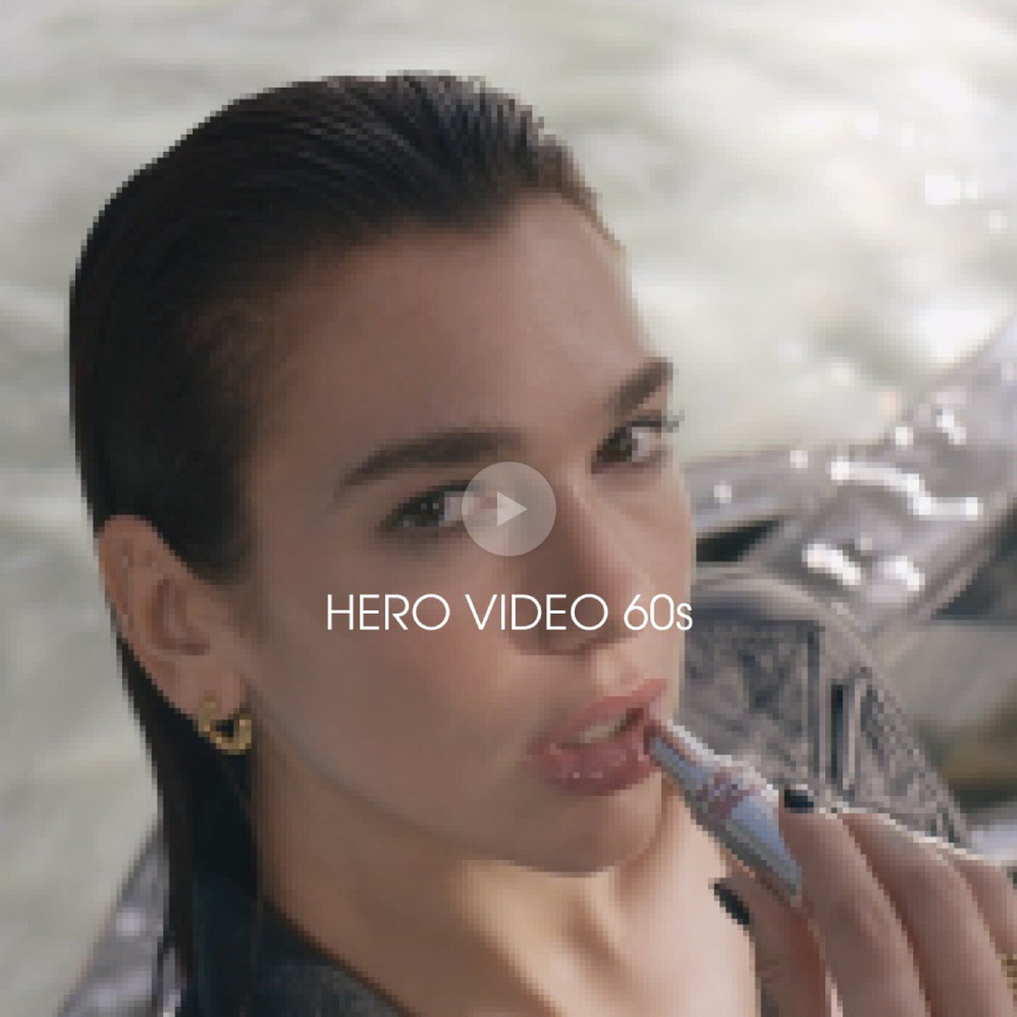 A model in a sheer black blouse poses by a pool, holding a lipstick while looking directly at the camera with a confident expression.