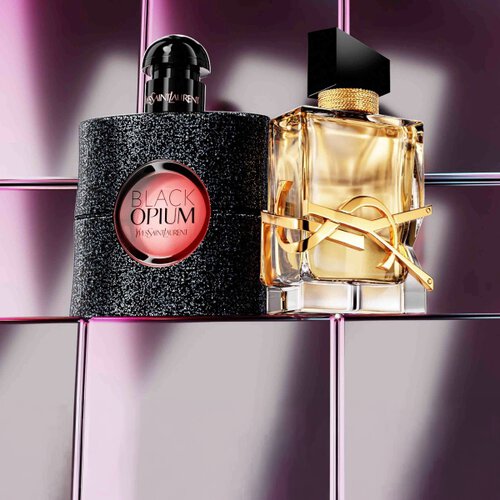 YSL Beauty-Produkte, darunter eine gesteppte Dose, Mascara und zwei Lippenstifte vor glanzendem, rosa gefliestem Hintergrund.