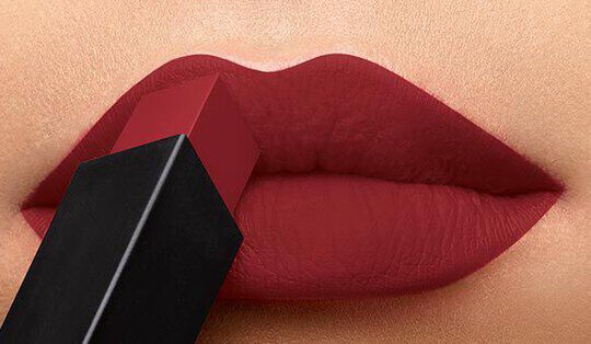 Close-up of a pair of lips being applied with a deep red lipstick.