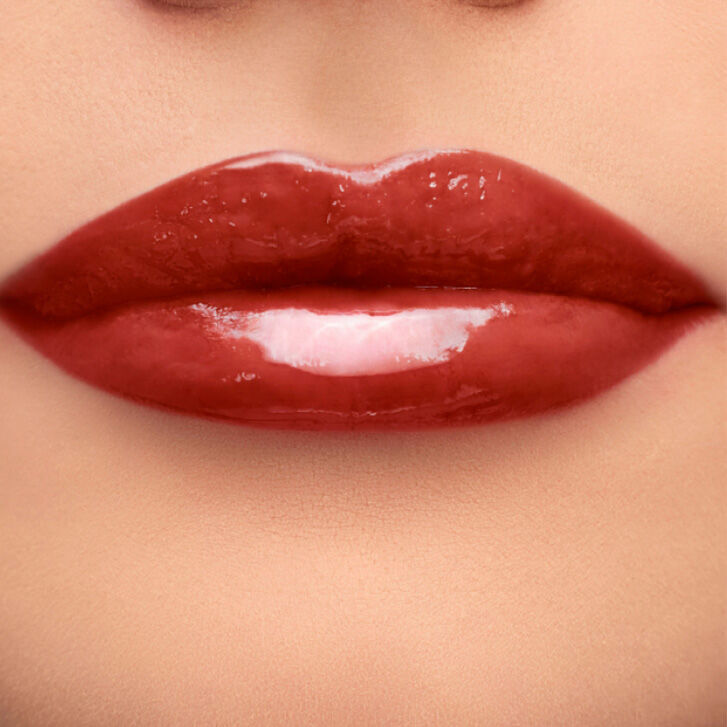 Close-up of a pair of glossy, well-defined lips with a rich, deep red color.