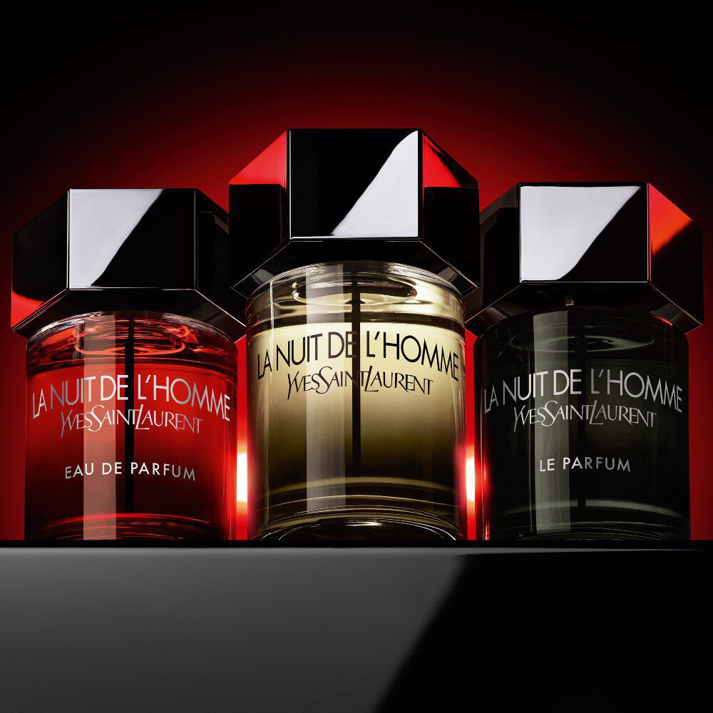 The La Nuit de l’Homme collection—Eau de Parfum, Eau de Toilette, and Le Parfum— displayed together against a dramatic red and black background.