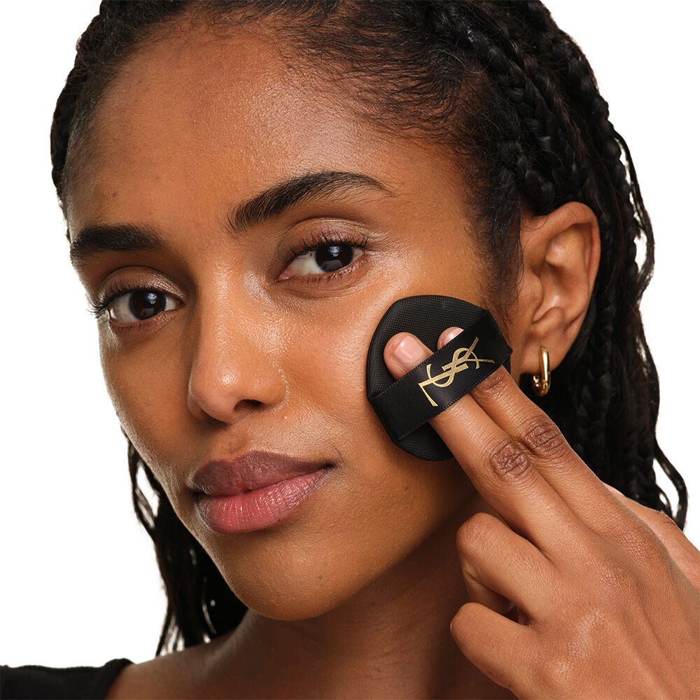 Model mit glatter, strahlender Haut halt das pinke YSL SKIN AFFAIR CUSHION FOUNDATION, um eine naturlich leuchtende, makellose Haut zu prasentieren.