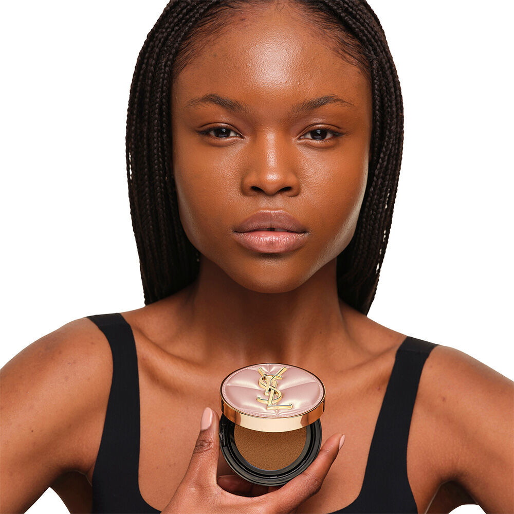 Model mit einer glatten, strahlenden Haut, die das rosafarbene YSL SKIN AFFAIR CUSHION FOUNDATION prasentiert, um ein naturlich leuchtendes, makelloses Hautbild zu zeigen.