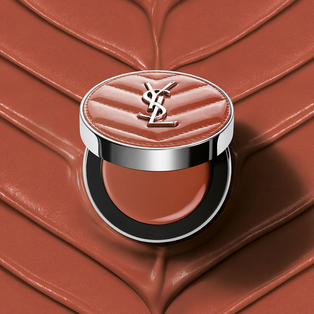 Ein offenes YSL Make Me Blush Lifted Glow Cream Blush Kompakt in Nuance #44 Nude Lavalliere auf einem passenden pinkfarbenen, strukturierten Creme-Hintergrund.