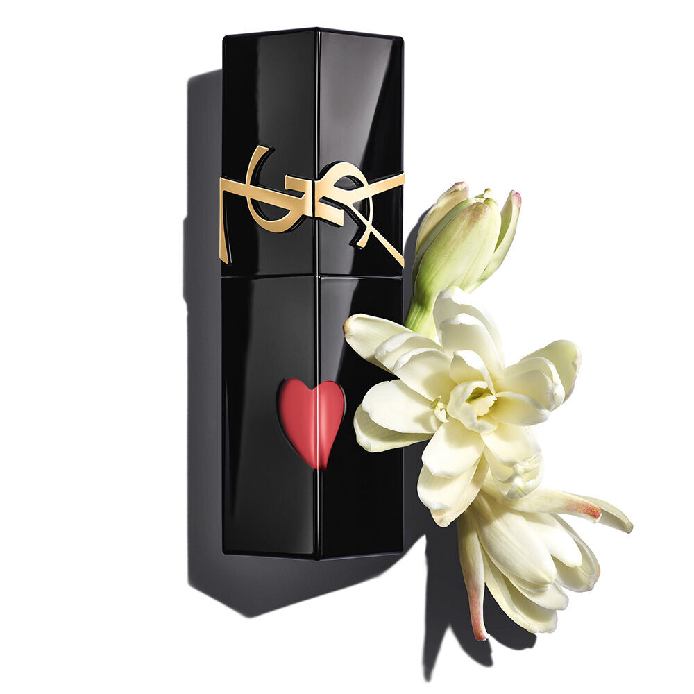 Ein glanzend schwarzer YSL Lip Stain Flakon mit einem roten herzformigen Ausschnitt, elegant prasentiert neben zarten, bluhenden weißen Tuberosen.