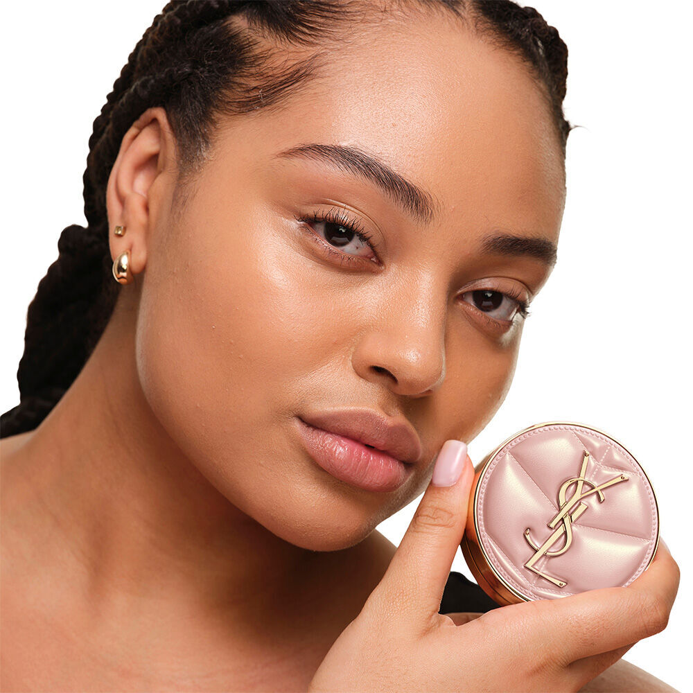 Model mit glatter, strahlender Haut, die das pinke YSL SKIN AFFAIR CUSHION FOUNDATION prasentiert – fur ein naturlich leuchtendes, makelloses Hautbild.