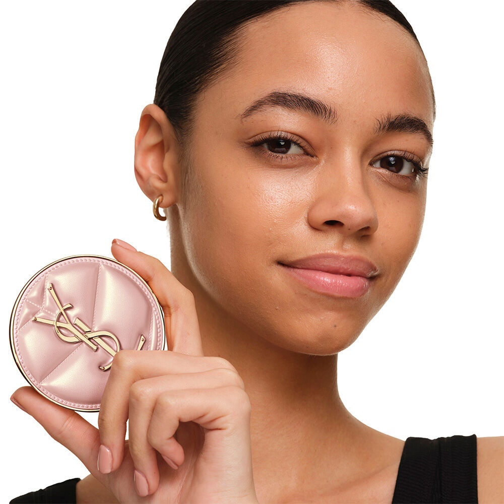 Model mit glatter, strahlender Haut, die das pinke YSL SKIN AFFAIR CUSHION FOUNDATION prasentiert, um einen naturlich leuchtenden, makellosen Teint zu zeigen.