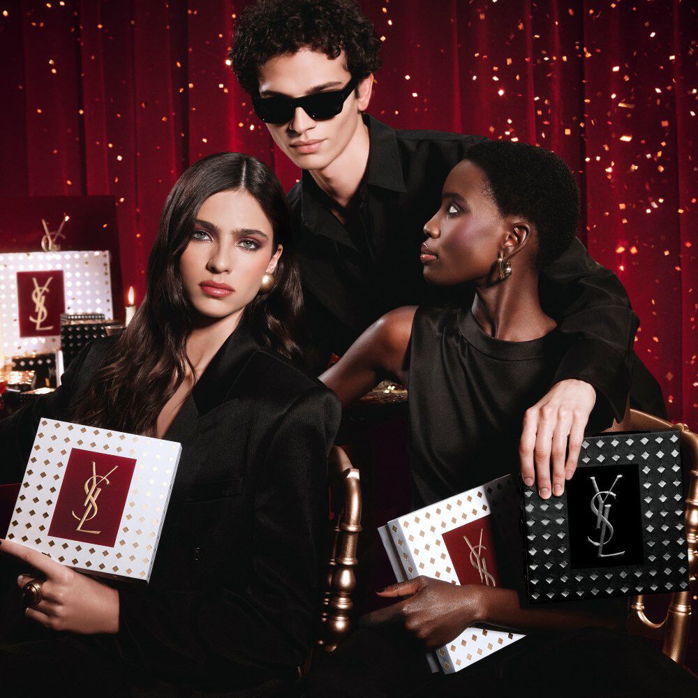 Modelle posieren gemeinsam, halten luxuriose YSL Festtags-Geschenkboxen in einer festlichen Atmosphare.