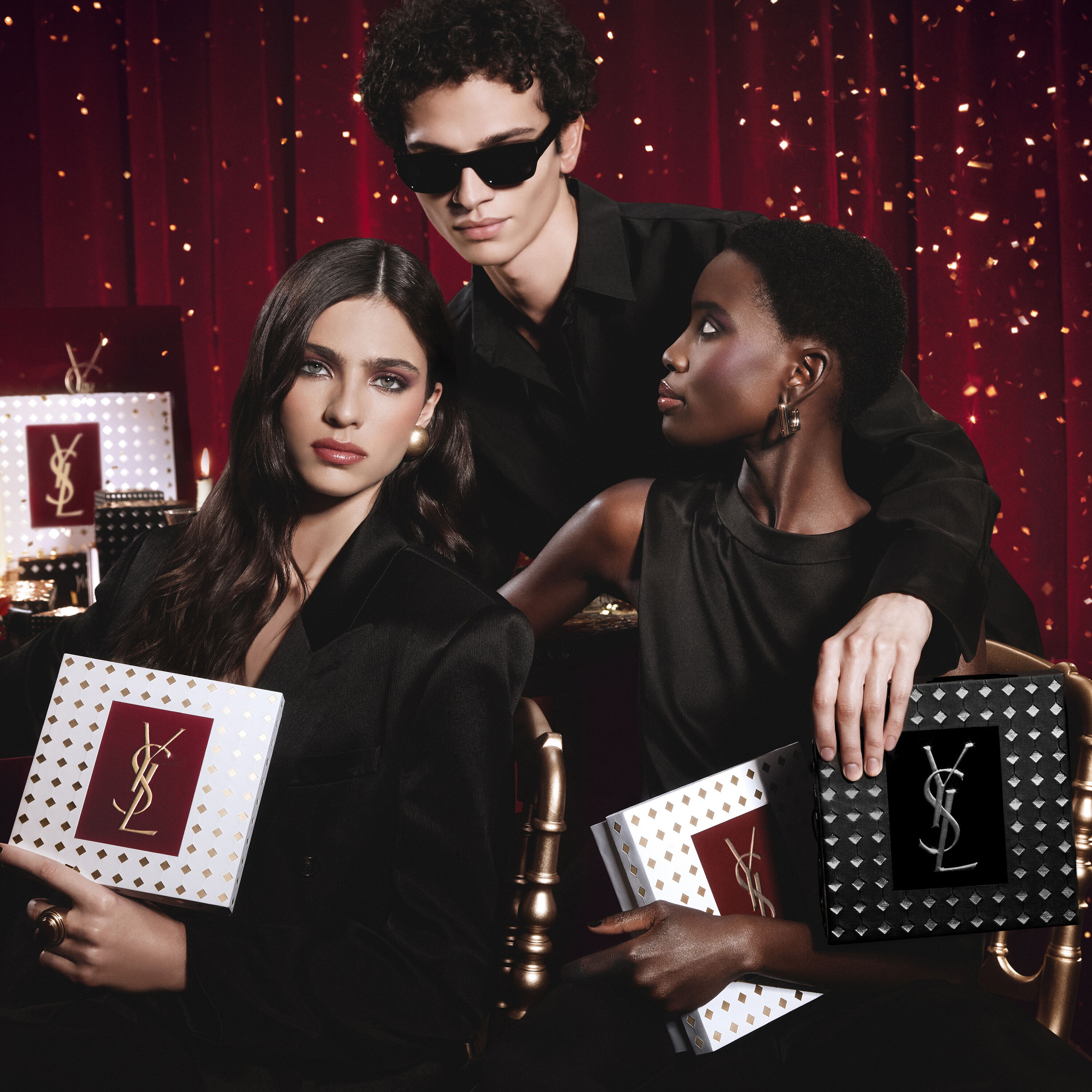 Modelle posieren gemeinsam, halten luxuriose YSL-Festtagsgeschenkboxen in einer festlichen Atmosphare.