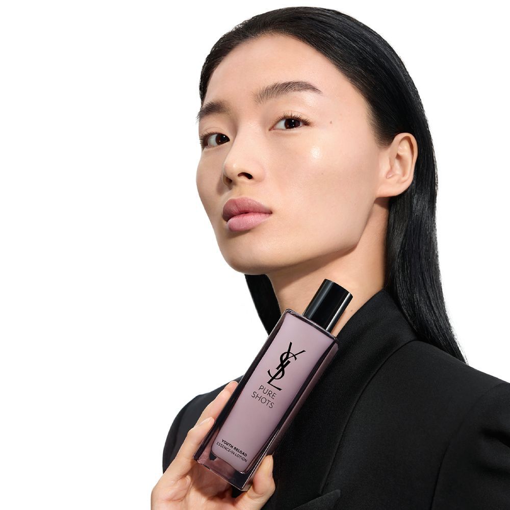 Wen, Model fur YSL Beauty, mit heller Haut, halt Pure Shots Youth Reload Essence-in-Lotion und betont die Feuchtigkeitsversprechen.