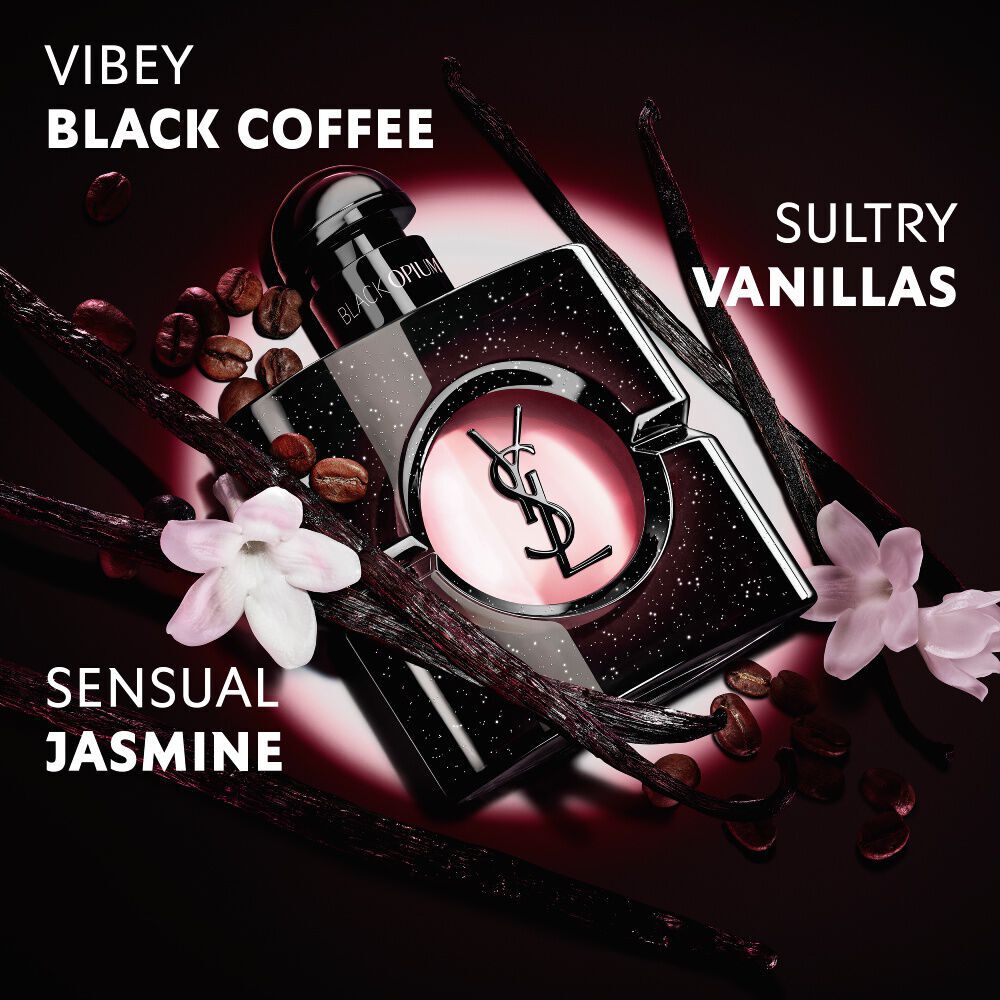 Nahaufnahme gerosteter Kaffeebohnen, Vanilleschoten und Jasminbluten, arrangiert uber dem ikonischen Flakon von Black Opium Eau de Parfum mit der YSL Cassandre.