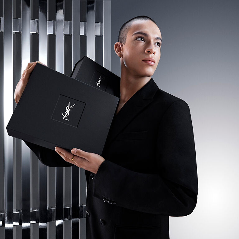 Pierre-Antoine, ein männliches Model, hält elegant eine edle schwarze YSL Beauty Geschenkbox mit dem ikonischen Cassandre-Logo.