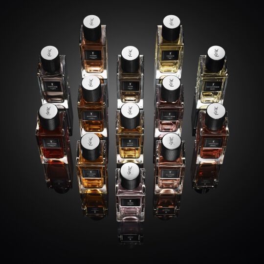 Eine Sammlung von YSL Parfümflakons auf einer spiegelnden, dunklen Oberfläche.