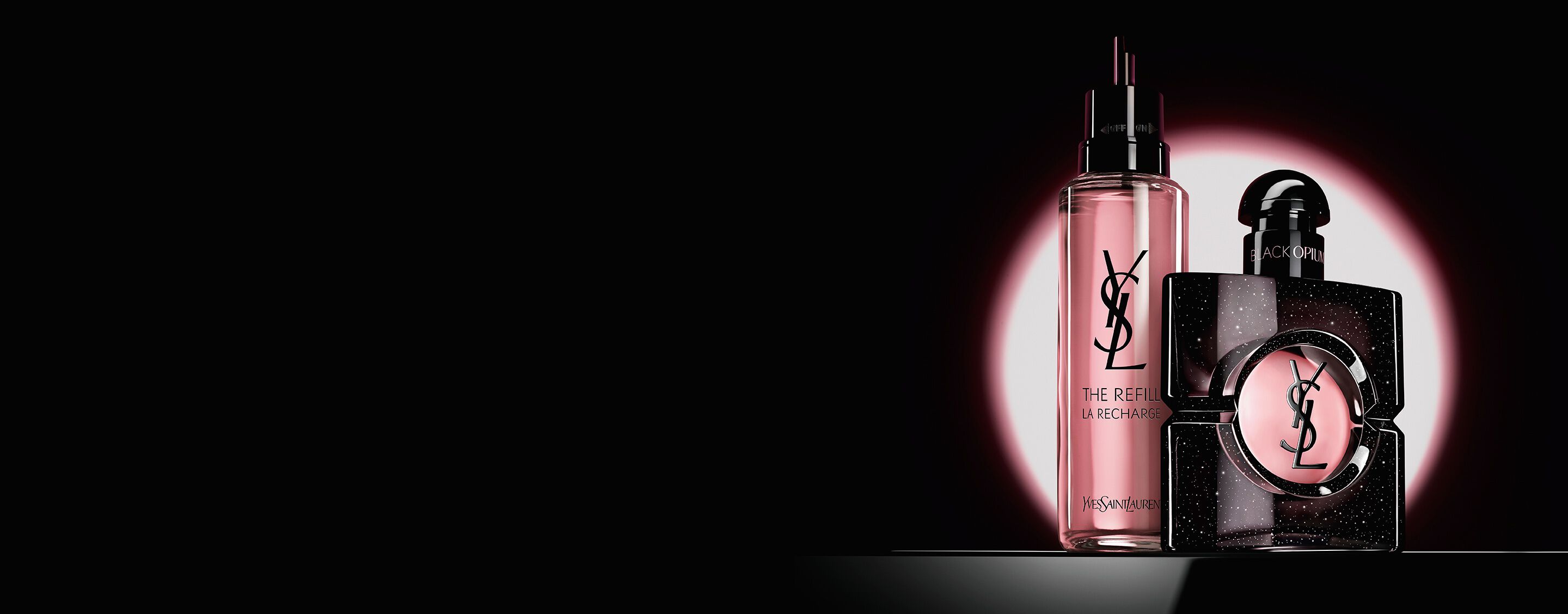 Black Opium Eau de Parfum Flakon neben seinem 100-ml-Glas-Nachfüllflakon mit dem YSL Logo.
