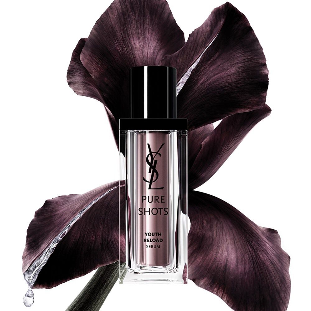 YSL Beauty Pure Shots Youth Reload Serum-Flakon, elegant vor einer dunkelvioletten Irisblüte platziert.
