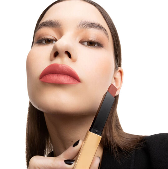 Hand hält einen geschlossenen schwarz-goldenen YSL Lippenstift.