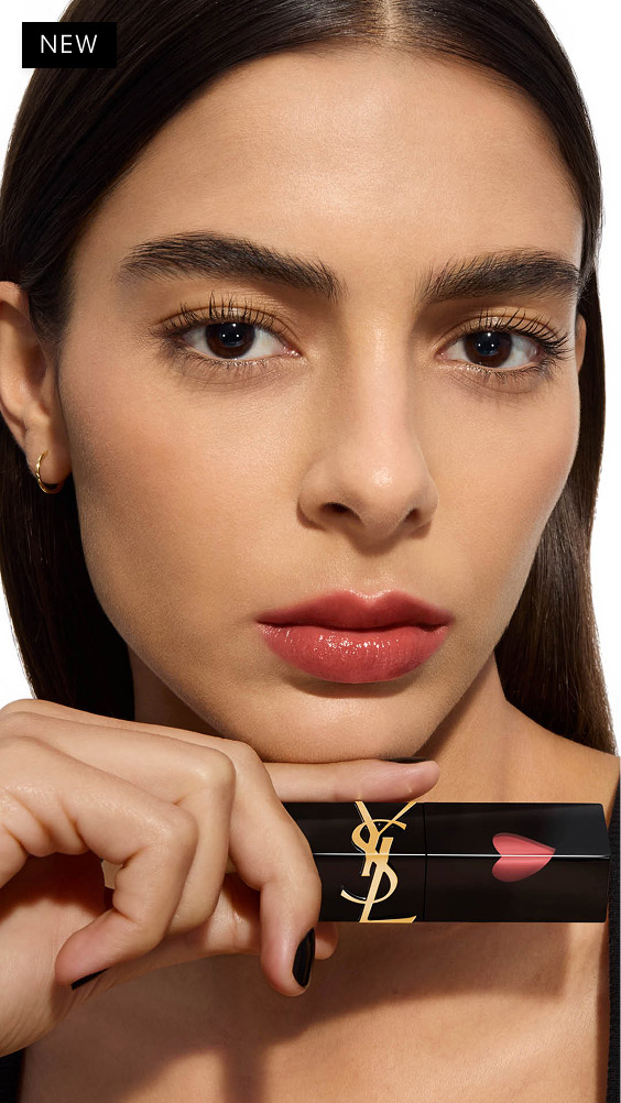Modell mit mittlerem Hautton posiert mit dem YSL THE INKS VINYL CREAM Lip Stain, waagerecht unter dem Kinn gehalten, zeigt einen warmen, glänzenden Rosé-Lippenfarbton.