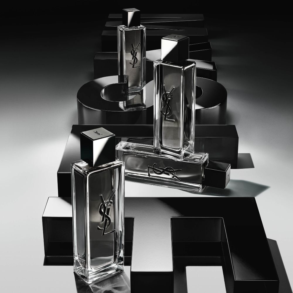 Ansicht von oben auf mehrere MYSLF Eau de Toilette Intense Flakons, die auf großen schwarzen 3D-Buchstaben angeordnet sind, die flach auf dem Boden den Schriftzug MYSLF bilden.