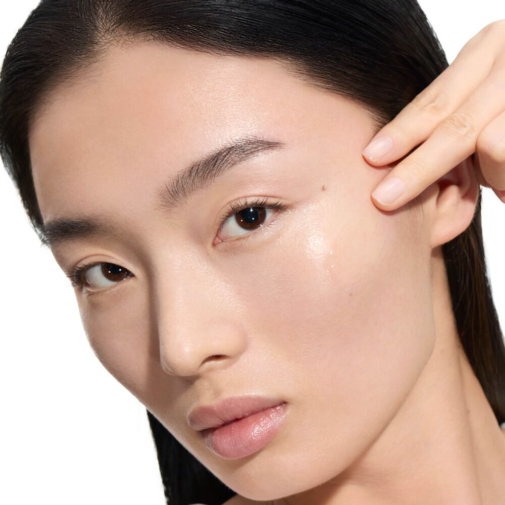 Wen, YSL Beauty Model, mit heller Haut, trägt einen Tropfen Pure Shots Youth Reload Serum auf ihre Wange auf.