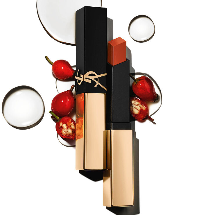 Quadratischer YSL-Lippenstift mit goldener Kappe zwischen roten Beeren und klaren Tropfen auf Weiß.