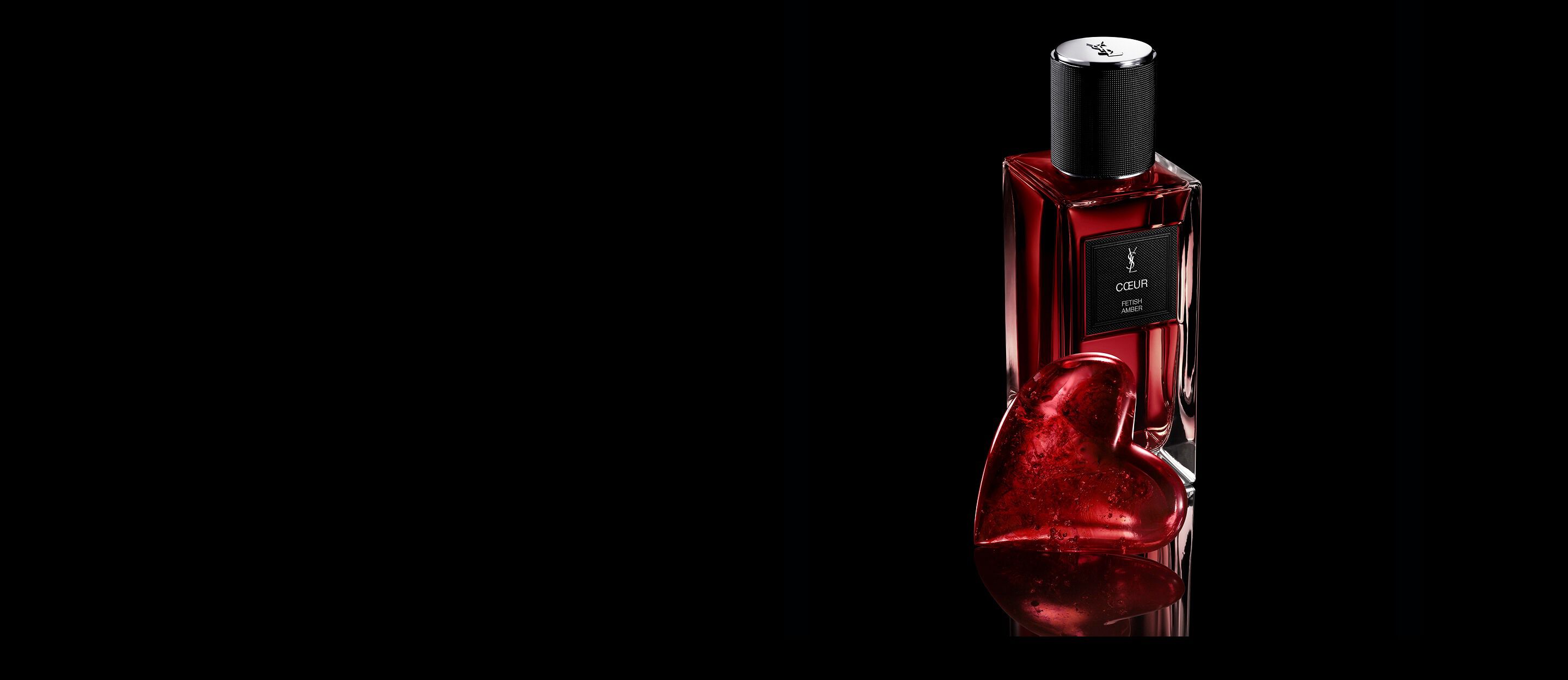 Flakon von CŒUR Eau de Parfum von YSL
neben einem rubinroten Herzjuwel auf einer
reflektierenden schwarzen Oberfläche.