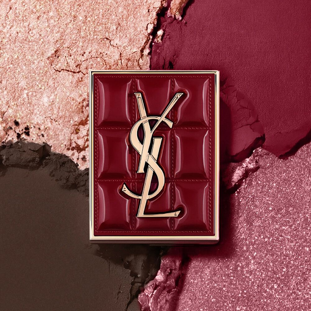 YSL Couture Mini Clutch Palette vor einem strukturierten Hintergrund aus schimmernden Lidschattenpigmenten in #1982 Burgundy Millesime.