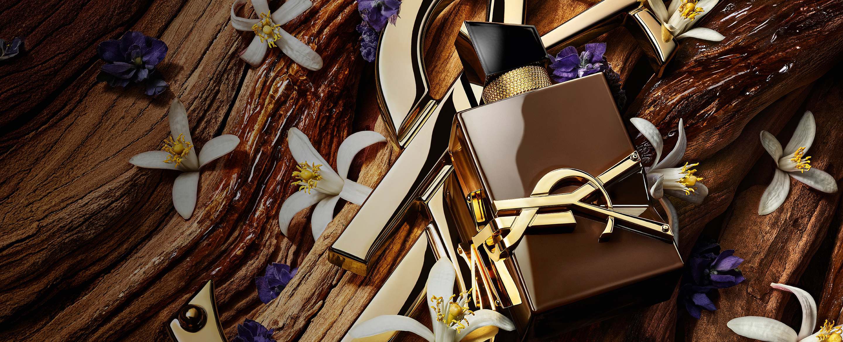 Glasierter brauner Libre Santal Couture Flakon, der das Licht reflektiert, auf einer großen goldenen YSL Cassandre platziert.