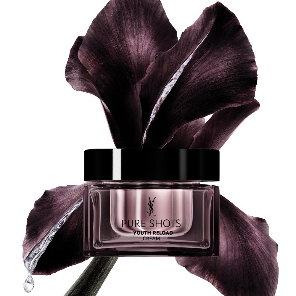 YSL Beauty Pure Shots Youth Reload Cream im eleganten Glas, stilvoll vor einer dunkelvioletten Irisblüte positioniert.