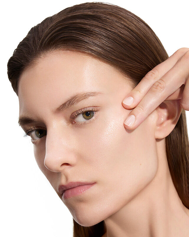 Marije, Modell für YSL Beauty, mit heller Haut, berührt sanft ihre Wange und zeigt glatte Haut nach der Anwendung der Lotion.